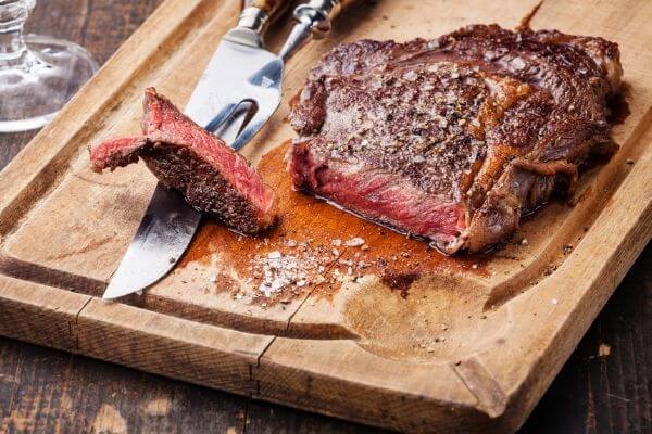 Medium rare cooked steak on a wooden cutting board