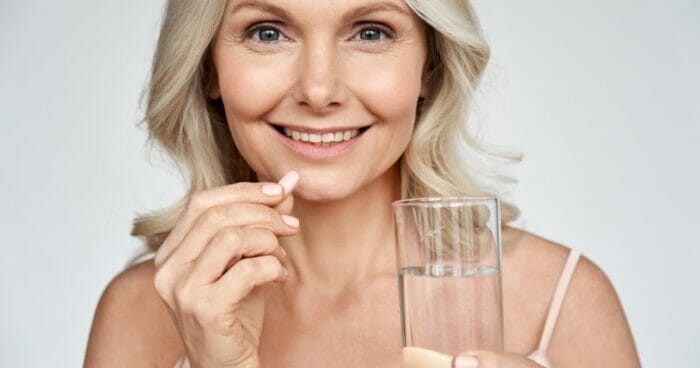 Older woman holding a supplement and glass of water